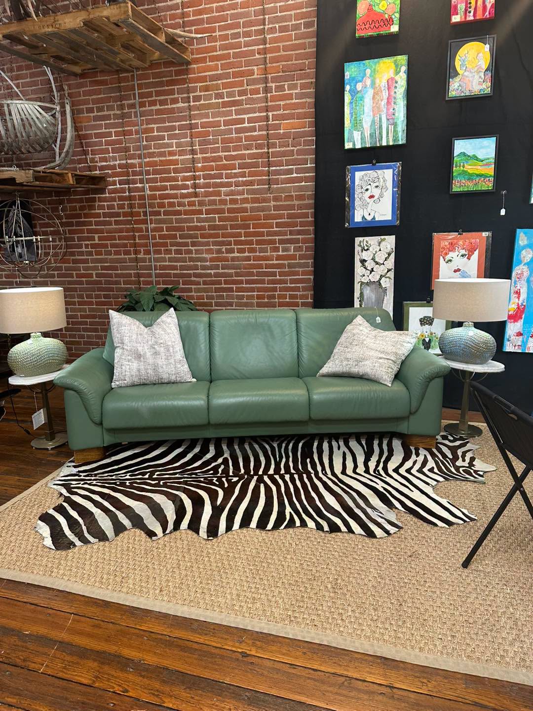 Deep green sofa with zebra rug and gallery wall